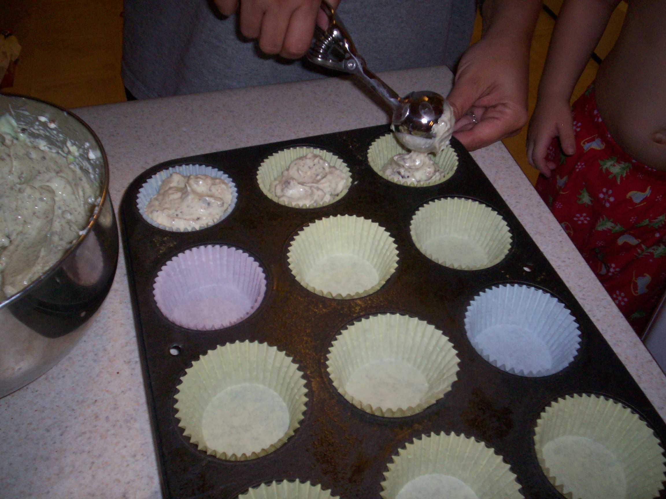 adding batter to muffin cups lined with paper