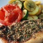 Herb grilled porterhouse with grilled tomatoes, squash, and zucchini. Pictured is the New York strip side of the steak.